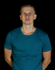 Fototapeta premium Blue t-shirt on young man isolated black background