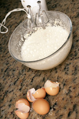 Four cracked eggs beside mixing bowl with batter