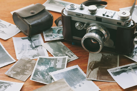 Film camera that had been popular in the past on a wooden table covered with photographs