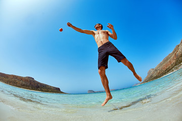 man standing in the sea on the beach. Smiling man looking at camera and He raises both hands up as if playing the ball