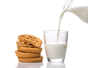 Pouring milk into the glass and cookies with jam isolated on white background