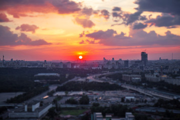 Tilt and shift view of sunset panorama of Moscow with red clouds and sun disk