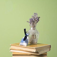 Dried lavender bouquet in a vase and lavender sachet bag standing on three old books.