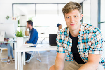 Fototapeta premium Young man sitting and looking at camera in office