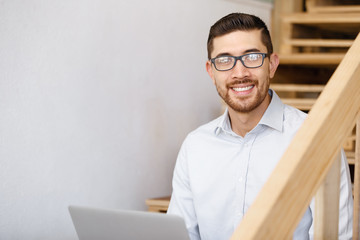 Fototapeta premium Portrait of young man sitting at the stairs in office
