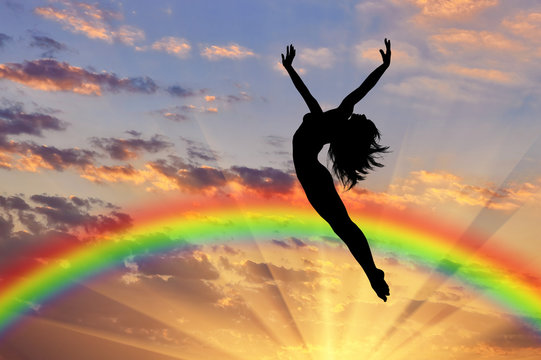 Happy woman jumping near rainbow