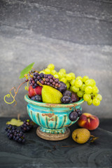 Beautiful still life with grapes and figs and other fruits on stone background.