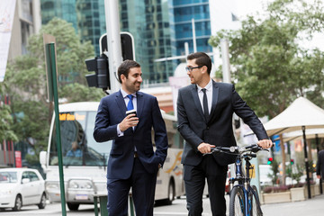 Two young businessmen with a bike in city centre