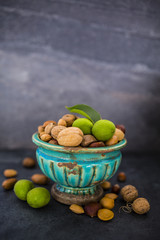 Nuts in old vase on a stone dark background. Beautiful autumn still life with copy space.