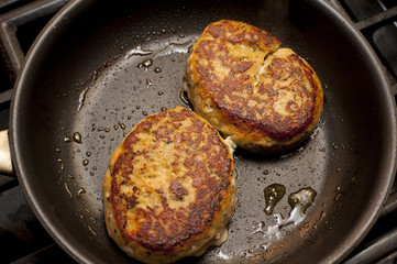 Crab cakes frying in pan