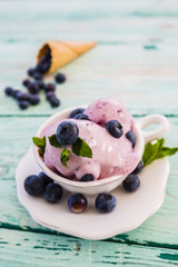 Blueberry ice cream and fresh blueberries on wooden table.