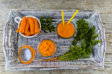 Fresh carrots and carrot juice on wooden background.