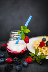 Yogurt with fresh berries fruit and crispy wafers on stone background.