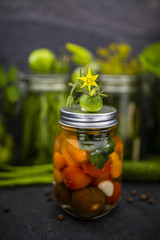 Jar of canned tomatoes and cucumbers jars in background.