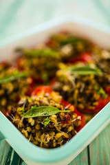 Stuffed red peppers with barley groats with vegetables and herbs  in dish at the wooden background. 
