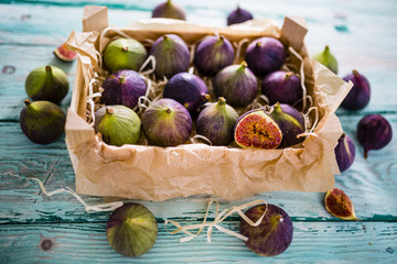 Ripe figs in a wooden box on a wooden table.