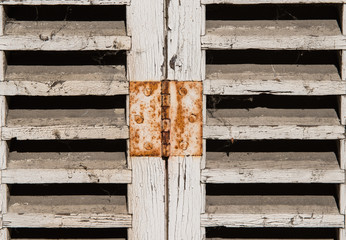 Detail of rusty hinge on old window shutter