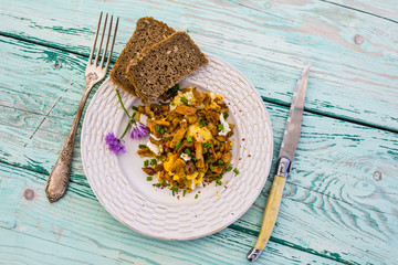 Delicious scrambled eggs with chantarelle mushrooms and chives on a wooden background