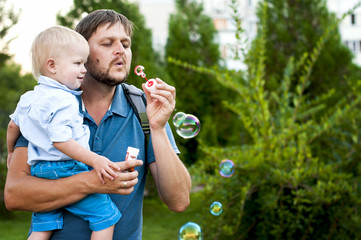 father and son is blowing a soap bubbles