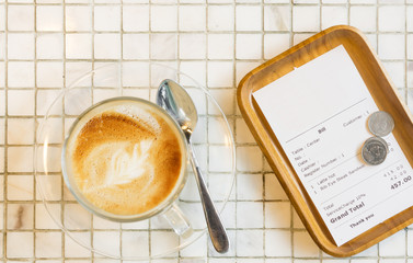 Bill receipt and coffee latte cup on white marble table