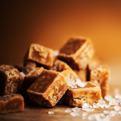 Caramel candies on brown background. Salted caramel pieces and s