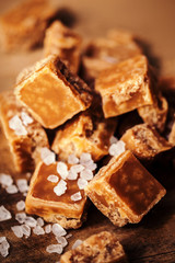 Caramel candies on brown background. Salted caramel pieces and s