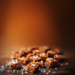 Salted caramel pieces and sea salt close up, top view. Buttersco