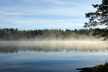 Foto op Canvas Prachtig uitzicht op het meer met vroege ochtendmist op het oppervlak van het meer, Finland. © sarijii