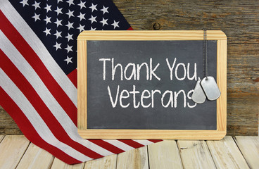 Fototapeta na wymiar thank you to veterans on black chalkboard with military dog tags on American flag