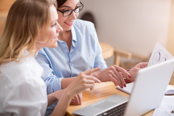 Two female colleagues using laptop