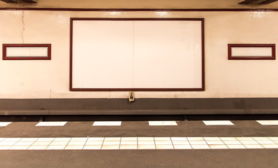 underground platform with empty advertising boards on the wall