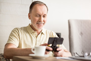 Joyful senior man sitting at the table