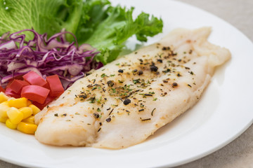 Grilled fish fillet steak with herb and vegetables on plate