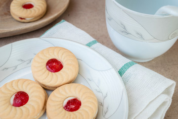 Sweet cookies with cream and jam on wood background
