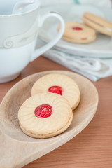 Sweet cookies with cream and jam on wood background
