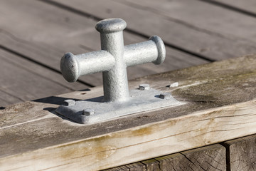 Small gray mooring bollard on wooden pier