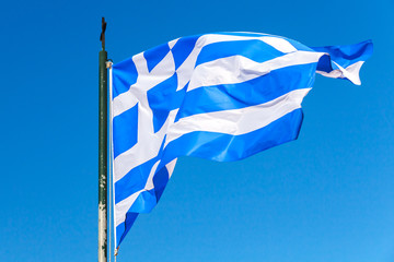 Flag of Greece waving over clear blue sky