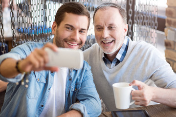 Cheerful man and his grandfather making selfies