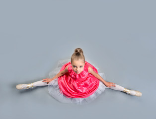 Little young ballerina girl in pink dress doing gymnastic split. © jutaphoto