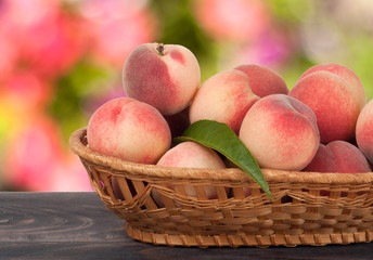 peaches in a wicker basket on  wooden table with  blurred background