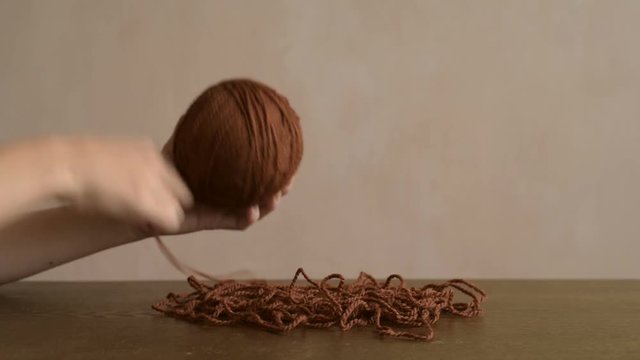 Female hands clewing the brown yarn up