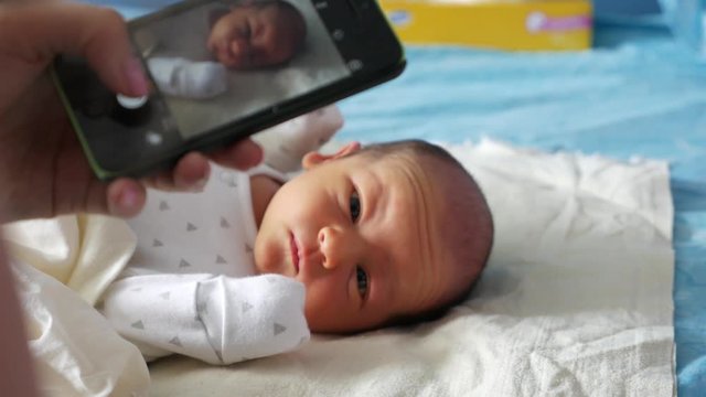 Mother making a photo of an infant with a touchscreen phone