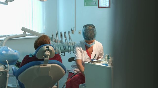 The dentist treats teeth of a young guy. 2 Shots