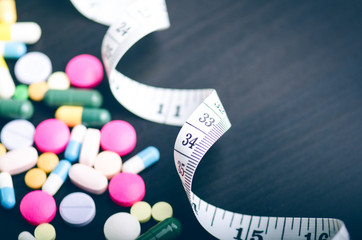 Pharmacy background on a black table with measuring tape. Tablets on a black background. Pills....