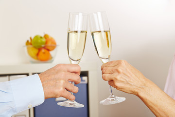 Alte Hände stoßen mit einem Glas Sekt an