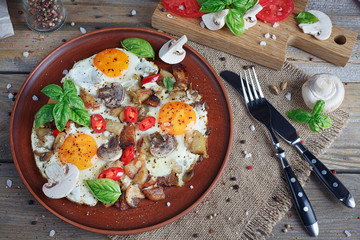 Fried eggs with mushrooms, tomatoes and basil on rustic wooden t