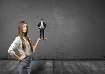 Cropped portrait of big businesswoman holding small businessman on her palm