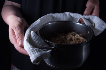 A pan with boiled buckwheat with mushrooms and onion in a woman'
