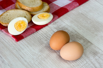 Eggs and bread on tablecloth over wooden background.