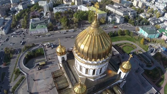 Flight around Cathedral of Christ the Saviour against background of city road and buildings Close up golden dome and cross Moscow Russia